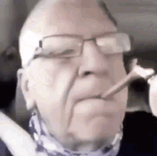 An older man on a webcam smoking and looking pleased about it.